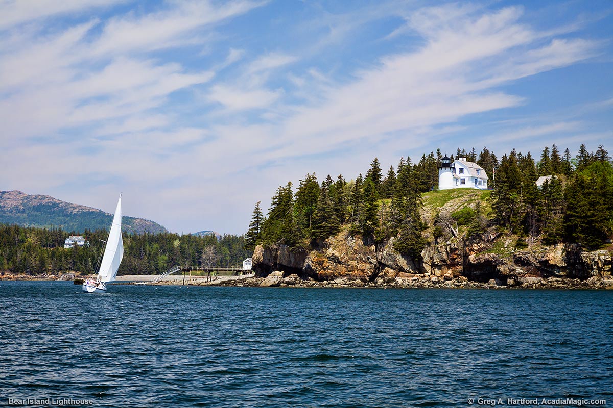 Mount Desert Island can be seen here behind the sailboat as it passes near the Bear Island Light Station.