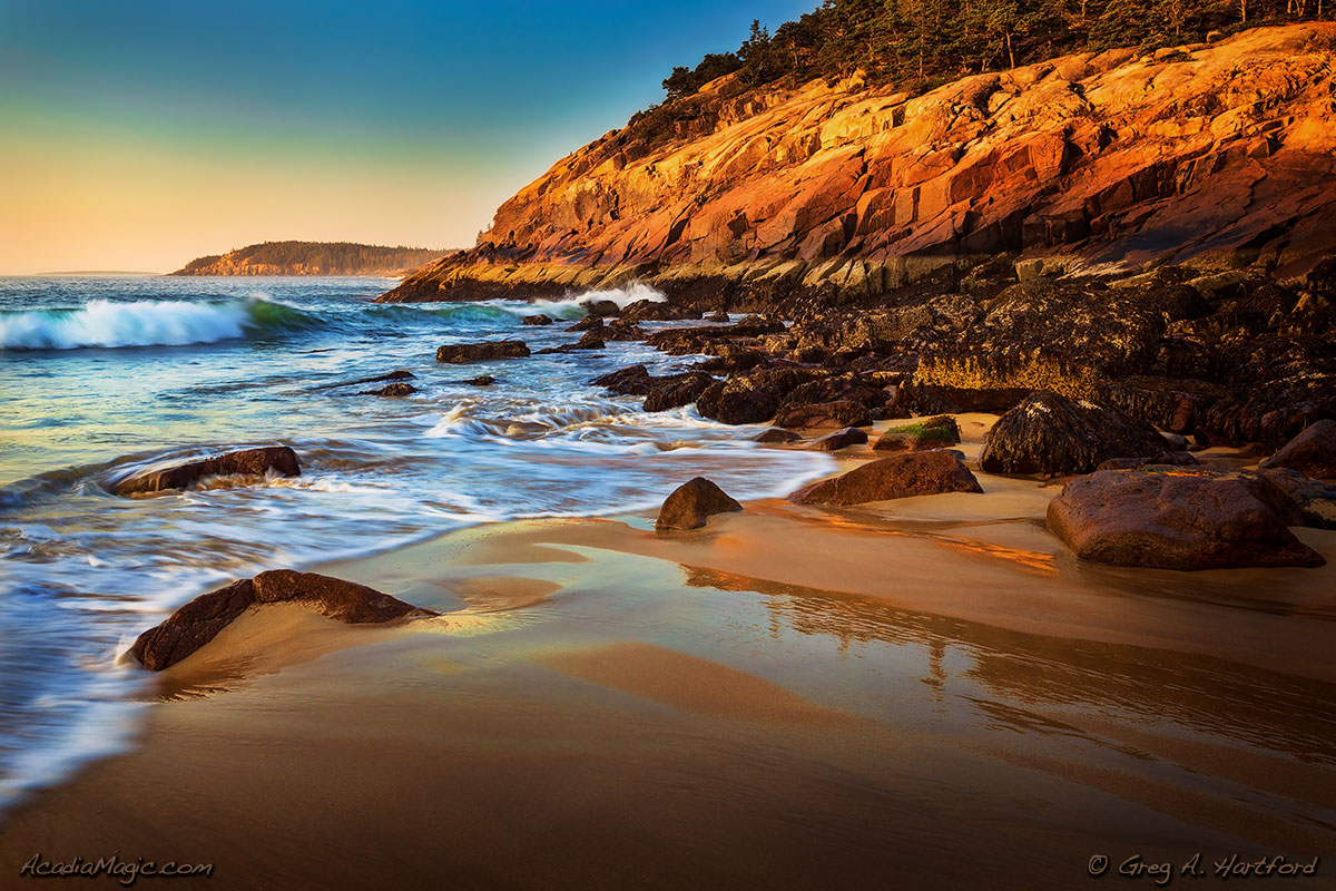 Golden morning sunlight shines on the pink granite at Sand Beach in Acadia National Park, Maine.
