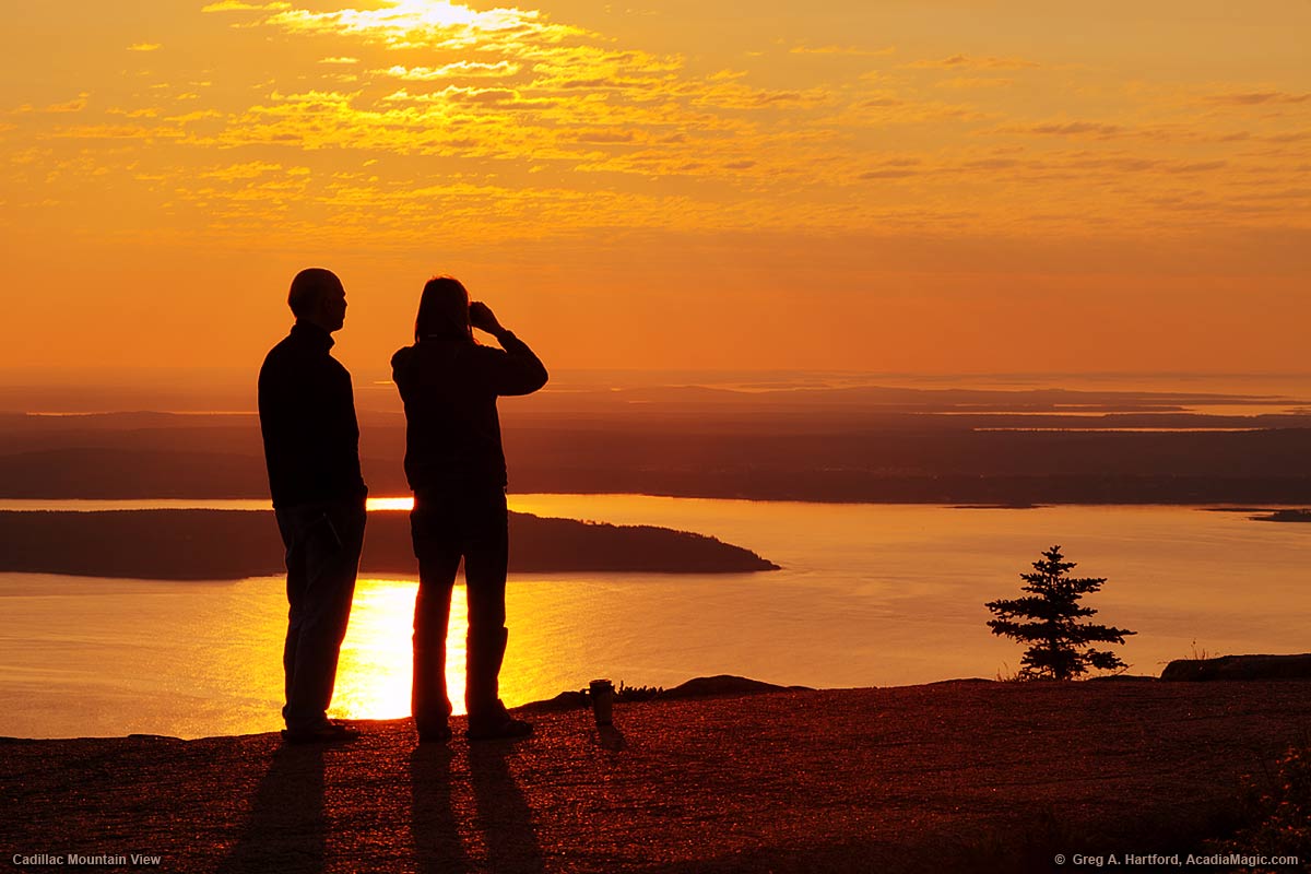 A couple pauses on the Cadillac Mountain summit path to view distant islands.